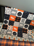 Double Minky baby blanket in navy, orange and gray with a woodland theme incorporating deer, arrows, canoes, antlers and mountains