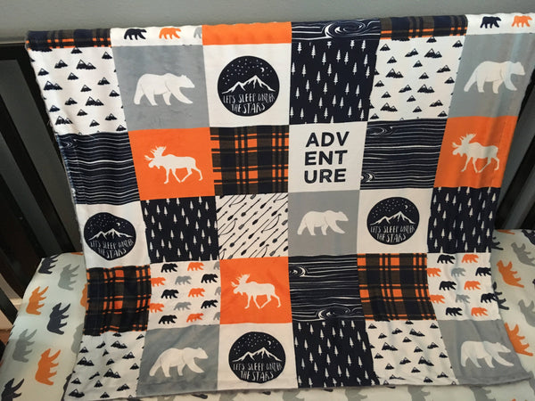 Double Minky baby blanket in navy, orange and gray with a woodland theme incorporating deer, arrows, canoes, antlers and mountains