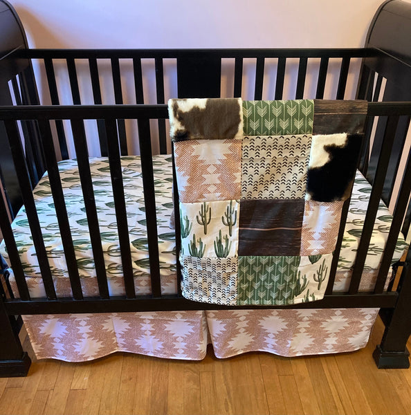 Custom Baby Bedding with a western boho theme with cow hide, cactus, Aztec, succulents, in neutral colors, tan, green, and brown
